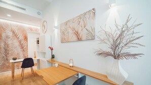 A modern interior with a wooden dining table, two chairs, a vase with dried plants, and wall art. - ARCASuite Trevi (Rome)
