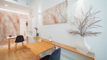 Ein modernes Interieur mit einem Holzespeisetisch, zwei Stühlen, einer Vase mit Trockenpflanzen und Wandbildern.