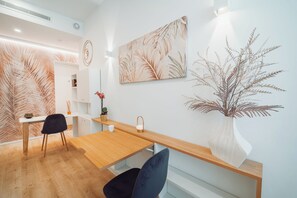 A modern interior with a wooden dining table, two chairs, a vase with dried plants, and wall art. - ARCASuite Trevi (Rome)