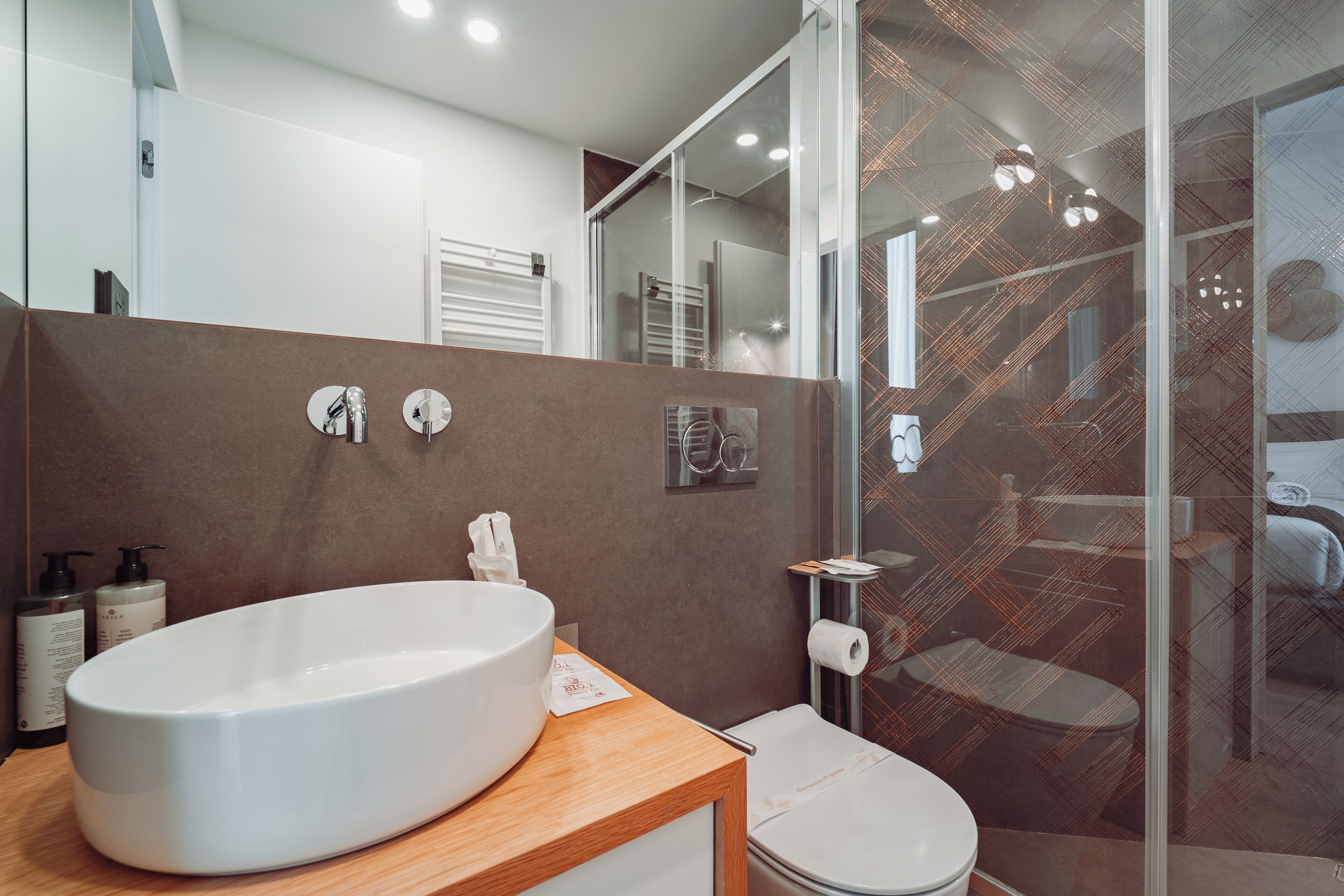 Un bany modern amb un gran lavabo blanc, un vàter i una cabina de dutxa de vidre.