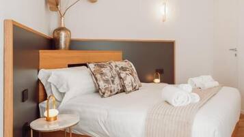 Un dormitorio ordenado con una cama de madera, mesitas de noche y un jarrón con ramas secas.