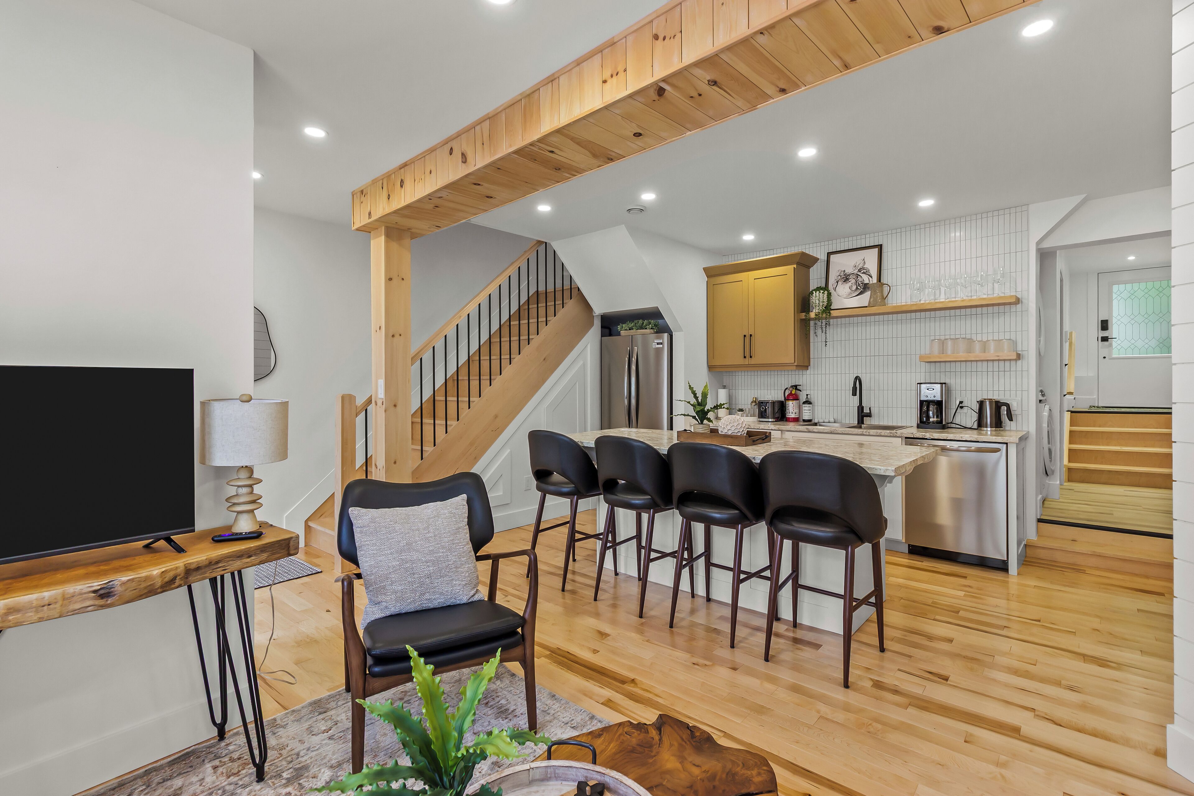 A modern kitchen with a central island, built-in appliances, and a wooden staircase.