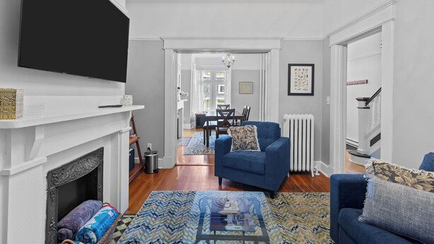 A living room with a fireplace, a television, a blue sofa, and a patterned rug.