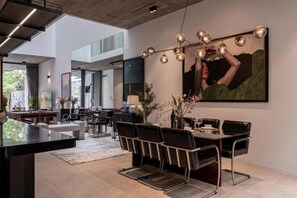 Un espace de salle à manger moderne, doté d’une grande table, de chaises et d’un lustre original.