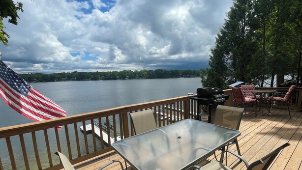 Une terrasse avec une table et des chaises, un drapeau américain et une vue sur un lac.