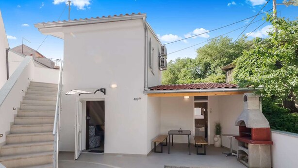 A residential property with a staircase, a covered patio area with a table and chairs, and a stone oven. - Peaceful Holiday Home Near Baska (Baska)