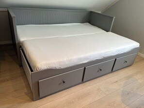 A bed with a grey frame and storage drawers, a wooden floor, and a sloped ceiling. - Newly built single-family home with its own spa area (Telemark)
