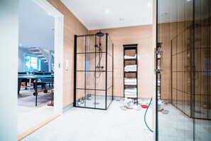 A modern bathroom with a glass shower enclosure, a built-in towel rack, and a visible trash bin. - Newly built single-family home with its own spa area (Telemark)