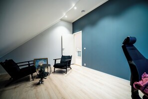A room with a sloped ceiling, a small Christmas tree, a framed painting, and a chair. - Newly built single-family home with its own spa area (Telemark)
