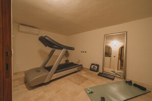 A home gym with a treadmill, a mirror, a yoga mat, and a small plant. - Elite Collection - The Olea Sanctuary  (Olbia)