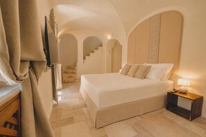Een slaapkamer met een bed, nachtkastje, lamp en een trap naar een hoger gelegen verdieping.