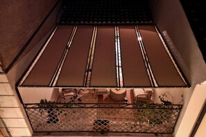 Ein Balkon mit Metallgeländer, Ziegeldach und Gartenmöbeln.