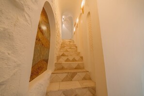Een wenteltrap met versierde treden die omhoog leidt, begrensd door witte muren met decoratieve details.