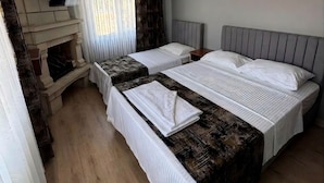 Habitación de hotel con dos camas, un televisor de pantalla plana montado en la pared, una ventana con cortinas traslúcidas y suelo de madera.