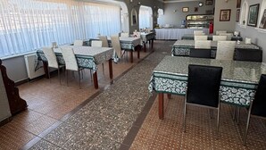 Un comedor con mesas y sillas, un área de cocina, y vistas a través de las ventanas.