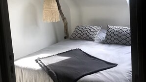 Un dormitori amb un llit, almoinos decorats, una làmpada penjant i una finestra.
