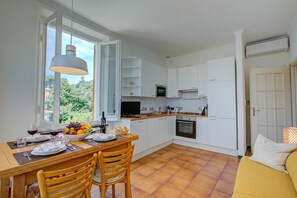 Une cuisine moderne avec des meubles blancs, une table à manger avec des chaises et une grande fenêtre.