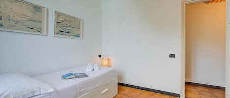 Una habitación con una cama, una lámpara de noche y dos cuadros en la pared.