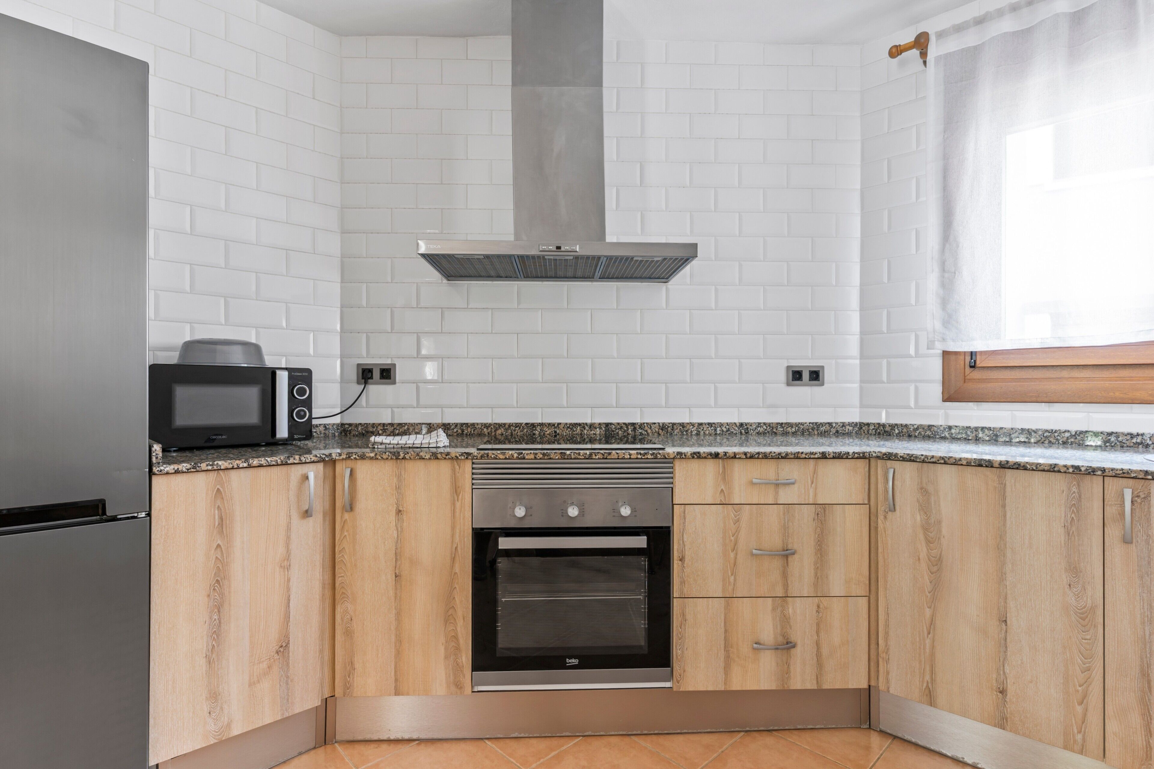 A kitchen with a built-in oven, microwave, and stainless steel refrigerator.