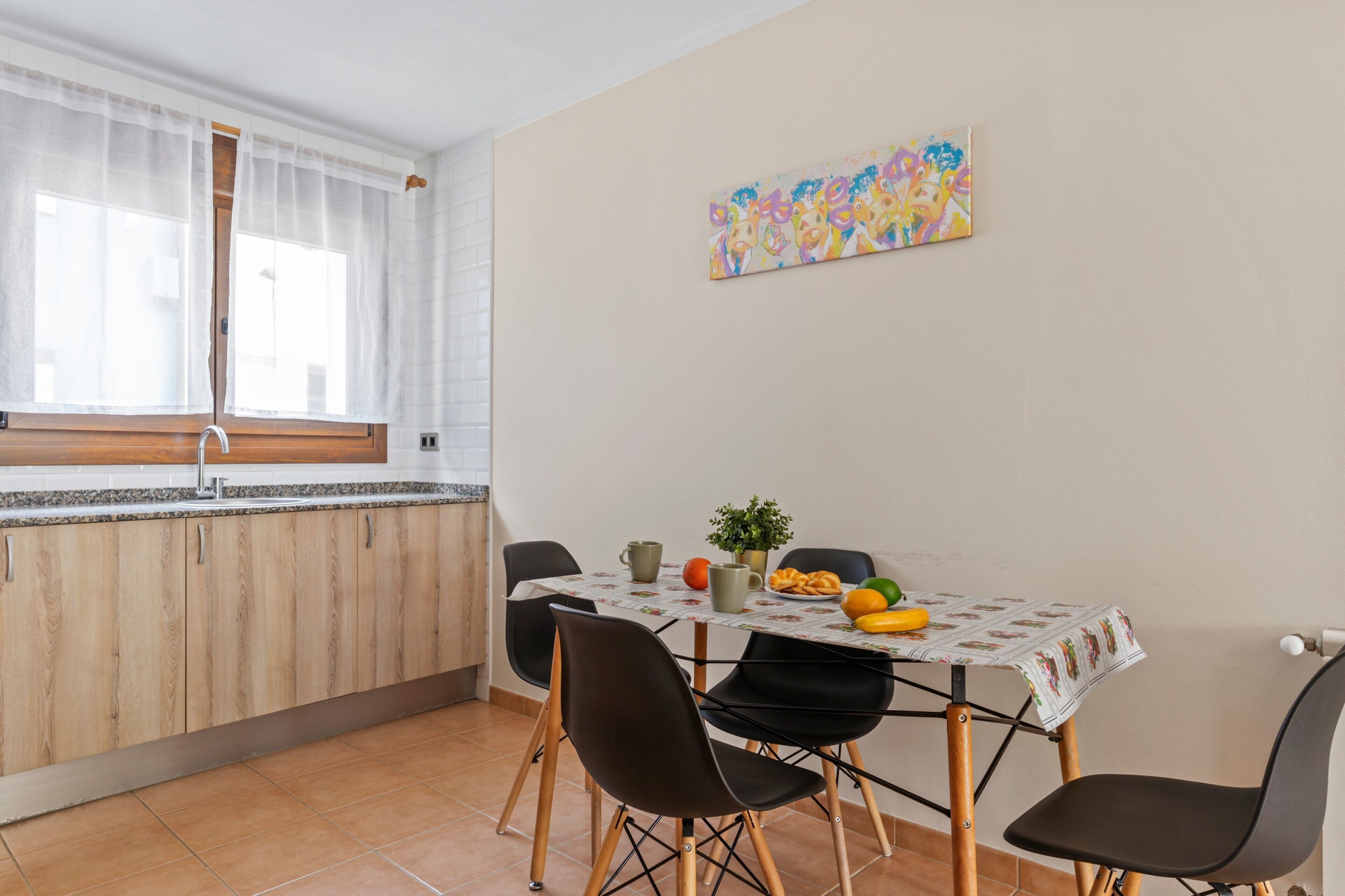 A dining area with a table, chairs, and a window with curtains.