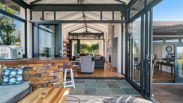 Un espacio habitable moderno y abierto con una pared de piedra, una mesa de centro de madera y un área de descanso con sofá y sillones.