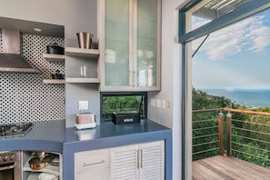Una cocina moderna con horno empotrado, panificadora y vistas al océano.