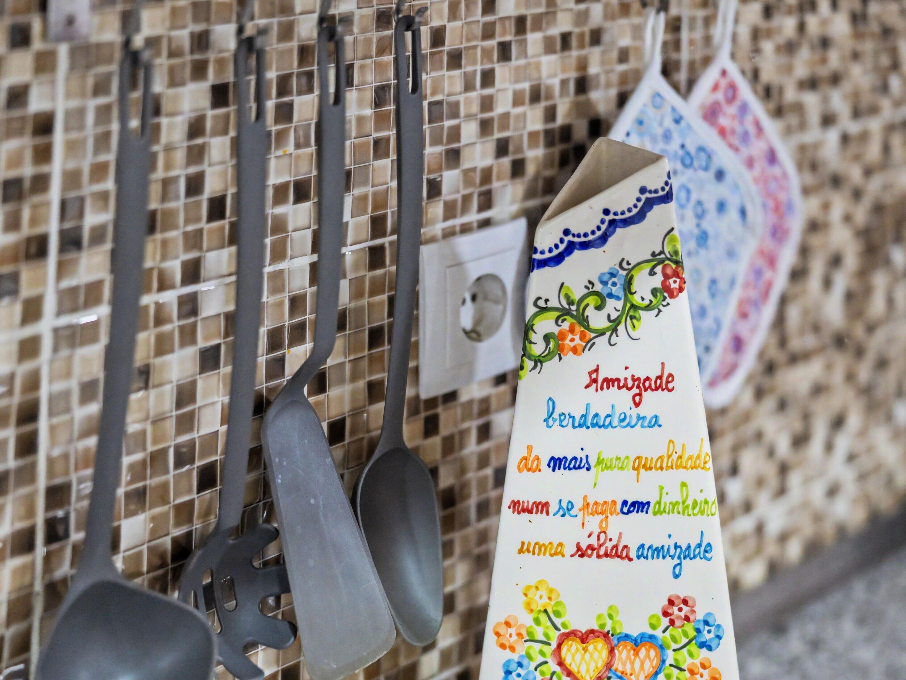 Des ustensiles de cuisine suspendus à un porte-ustensiles, avec une étiquette décorative.