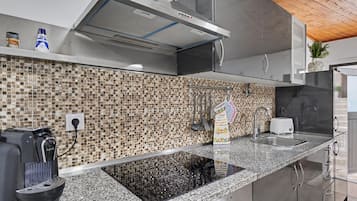Eine moderne Küche mit Granitarbeitsplatte, Edelstahlgeräten und einer Rückwand mit Mosaikfliesen.