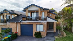 A two-story house with a garage, a balcony, and a small garden area.