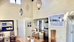A spacious kitchen with a wooden table, bar stools, and a large window.