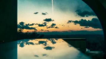 A sunset view through a semi-circular window with a clear reflection on the floor.
