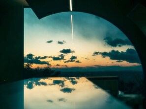 Vista al atardecer a través de una ventana semicircular con un reflejo claro en el suelo.