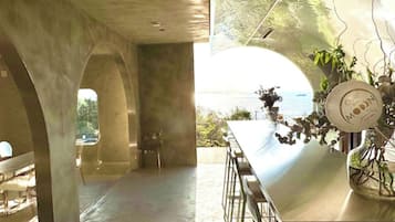Un interior moderno con vistas al mar, una zona de bar con un cuenco decorativo y un área de estar con sillones.