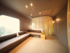 A modern interior with a curved ceiling, a sofa, a small table, and sheer curtains. - Over the MOON (Awaji)