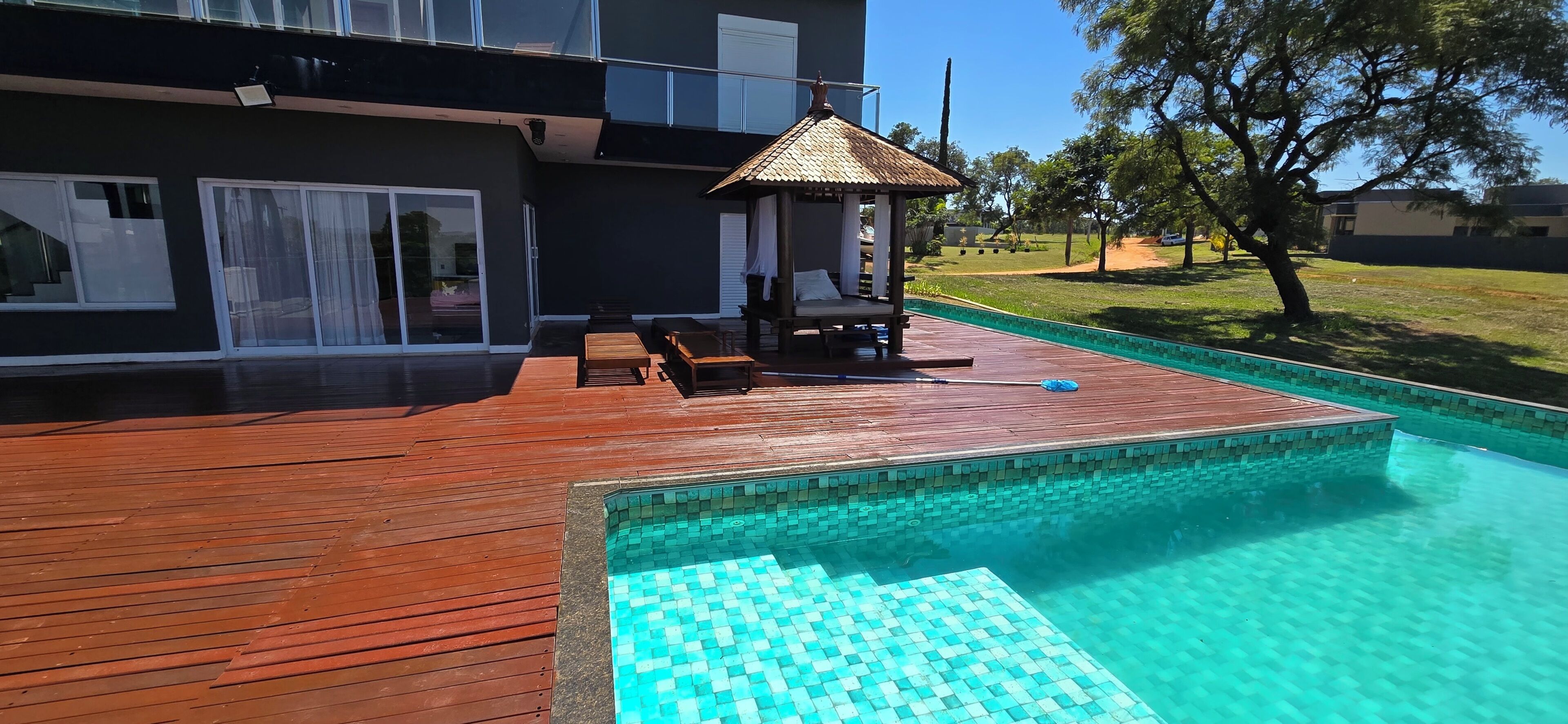 Une maison moderne dotée d’une piscine, d’une terrasse en bois et d’un espace salon aménagé et abrité.