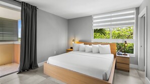 Ein modernes Schlafzimmer mit einem großen Bett, einem Nachttisch, einer Lampe und einem Fenster mit Jalousien.