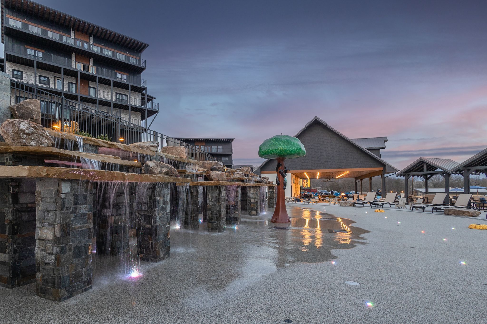 A modern building with a stone waterfall feature and outdoor seating area.