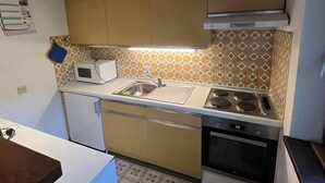 Cocina compacta con microondas, estufa y lavamanos.