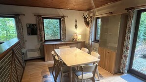 Un comedor con una mesa y sillas de madera, una cocina con ventana y una decoración de cabeza de ciervo en la pared.