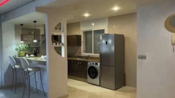 Een moderne keuken met een wasmachine, een koelkast en een eethoek met stoelen.