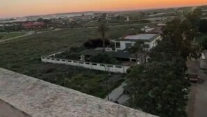 Een uitzicht op een woongebied met huizen en open velden, een heldere lucht en een verre horizon.