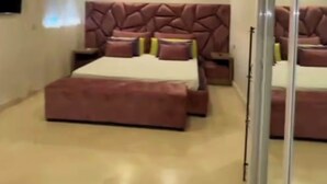 Een moderne slaapkamer met een groot bed, een glazen scheidingswand en een flatscreen televisie aan de muur.
