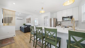 A modern kitchen with white cabinets, stainless steel appliances, and a central island with bar stools. - Pelican's Perch Cottage - New & Modern In Perfect Location w/ Waterfront Deck (St. Augustine)