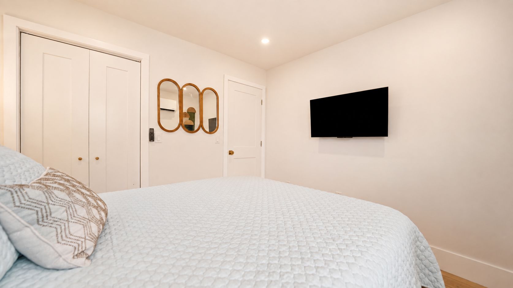 A bedroom with a bed, a wardrobe, a mirror, and a TV.
