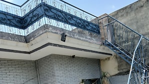 Un edificio en esquina con fachada de ladrillo, una escalera de metal y plantas en macetas.