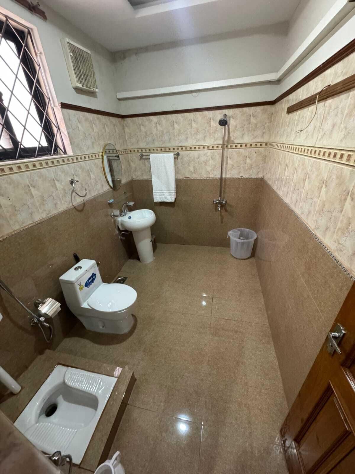 A bathroom with a toilet, bidet, and shower.