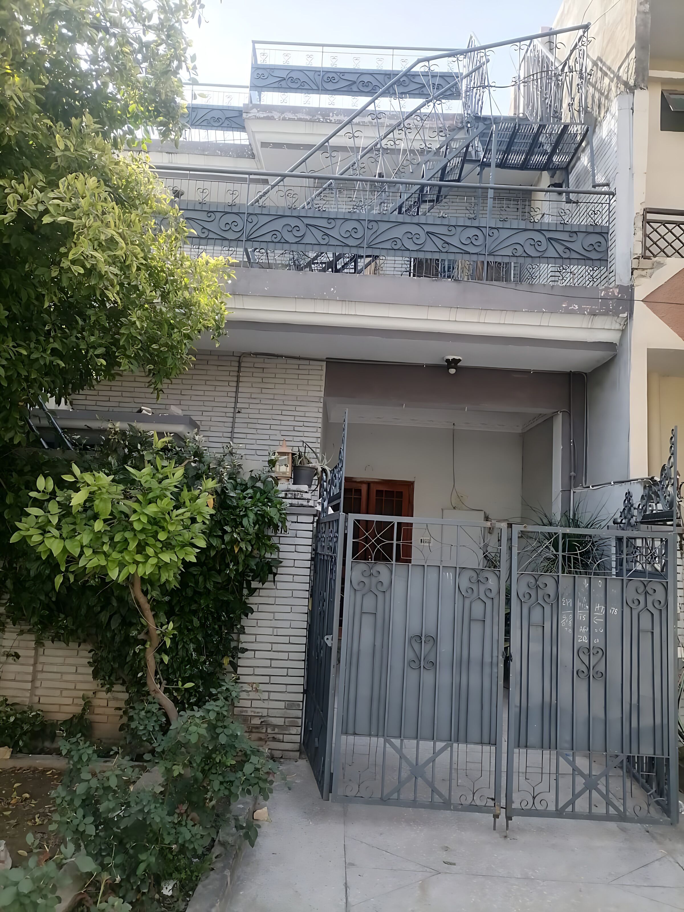 A residential building with a gated entrance, a staircase, and a balcony with railings.