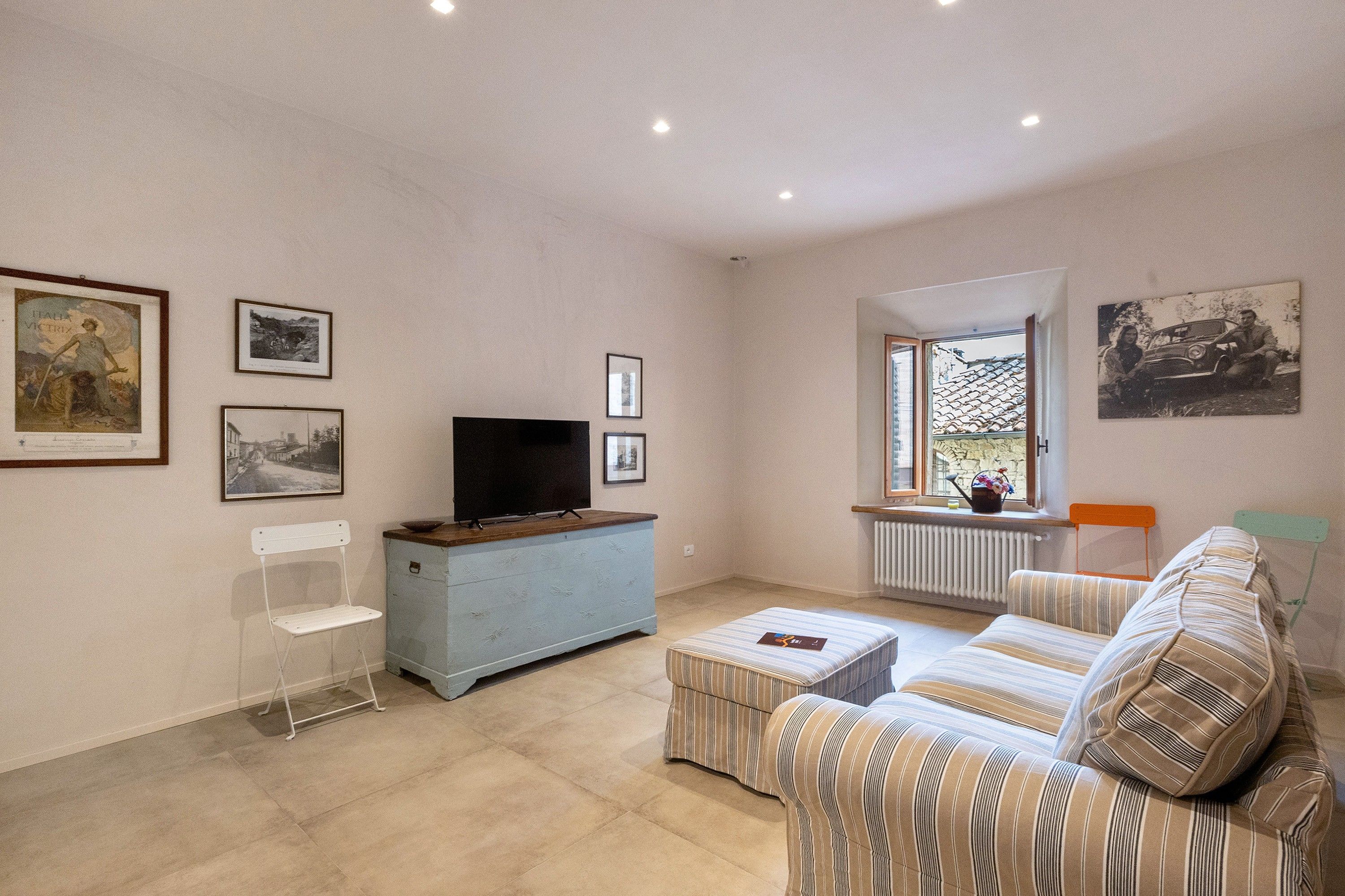 A living room with a television, a sofa, a small table, and framed pictures on the wall.