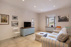 A living room with a television, a sofa, a small table, and framed pictures on the wall.
