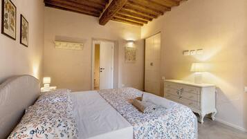 Une chambre à coucher avec un lit double, une commode, une table de chevet et une porte donnant sur une autre pièce.